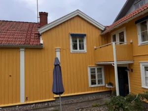 Nymålat gult hus i Gränna med vita detaljer vid entré och gårdssida.