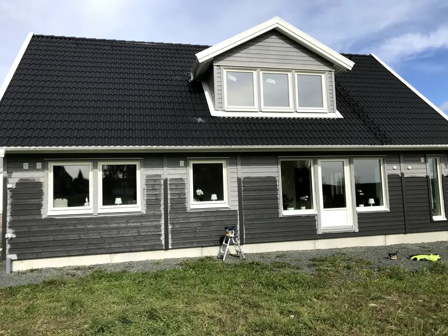 Framsida på villa i Vetlanda under fasadmålning med svart färg på träfasad