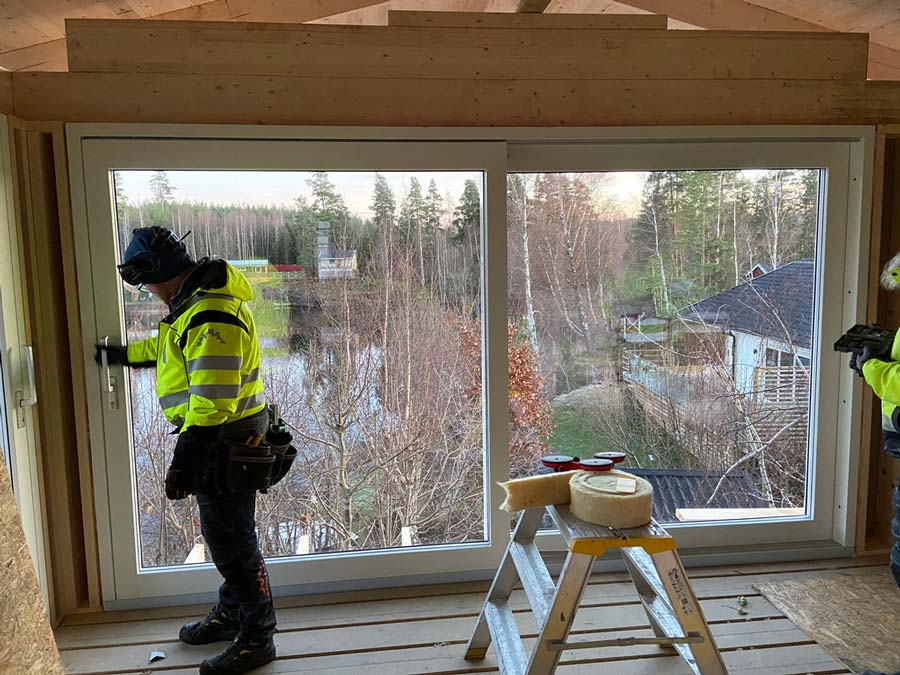 Fönstermontör monterar ett stort fönster inifrån i en villa