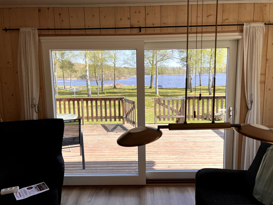 Nyinstallerad altandörr och nya fönster i ett trähus med utsikt över en sjö i Eksjötrakten