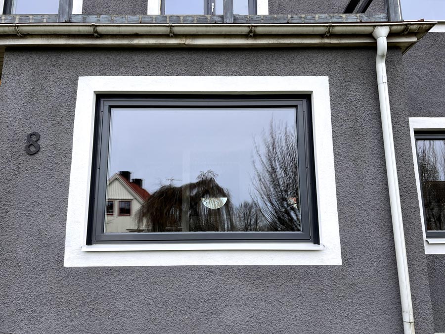Närbild på ett nytt fönster med mörk båge monterat på en villa