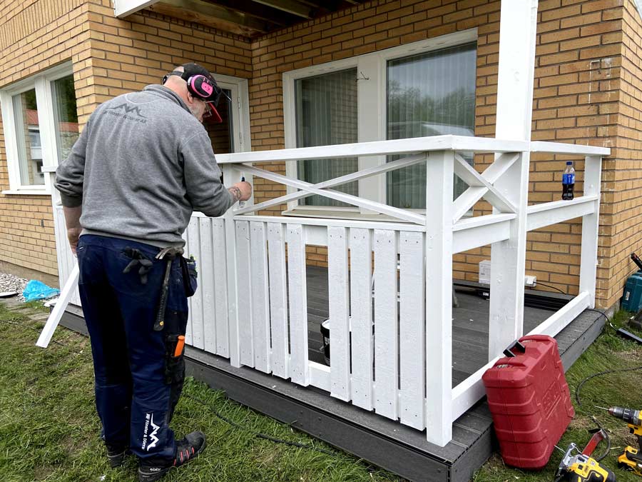 Snickare från AF Byggservice bygger vitt balkongräcke vid altanbygge i Värnamo