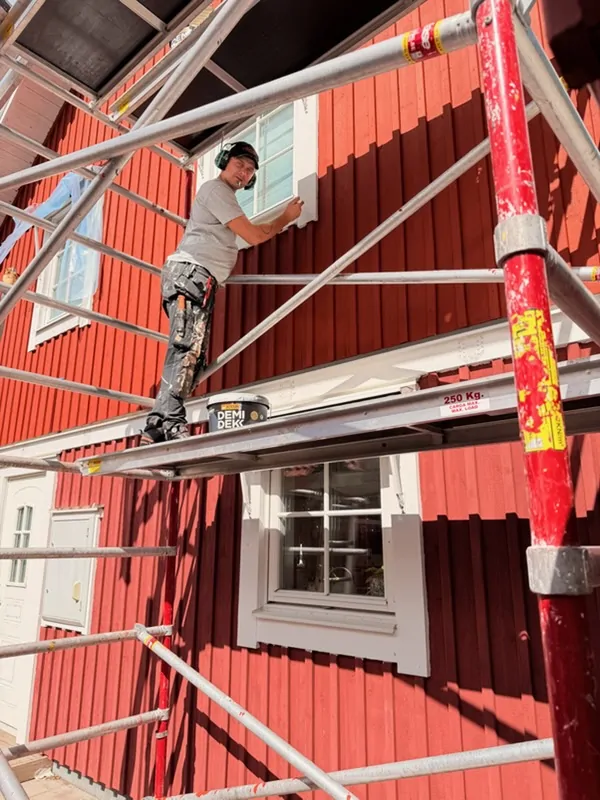 Målare från AF Byggservice målar om en röd träfasad från byggställning i Nässjö