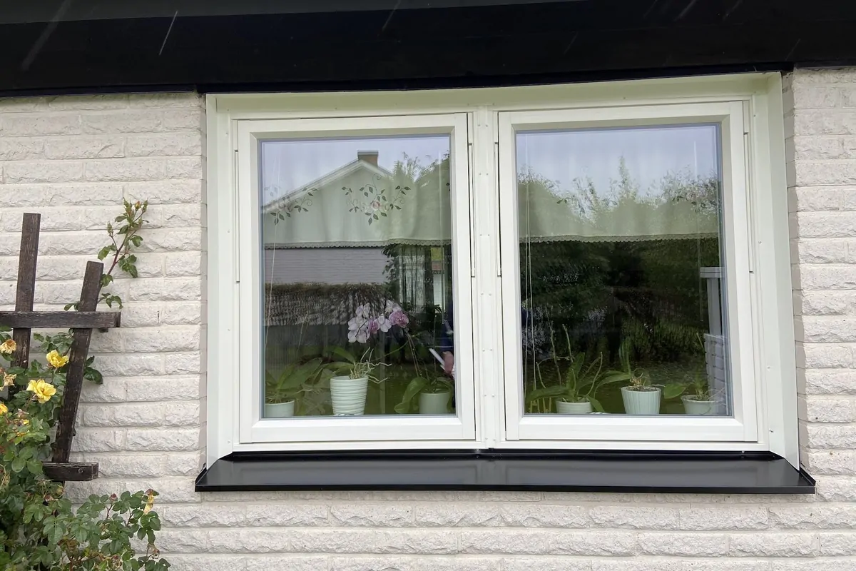 Nytt vitt tvåluftsfönster med svart fönsterbleck på villa i Vetlanda, monterat av AF Byggservice