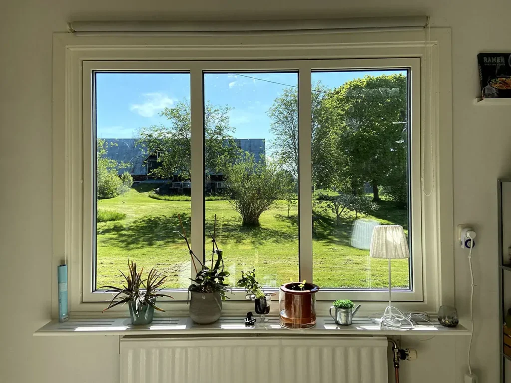 Ljust rum med fönster och utsikt över en grönskande trädgård