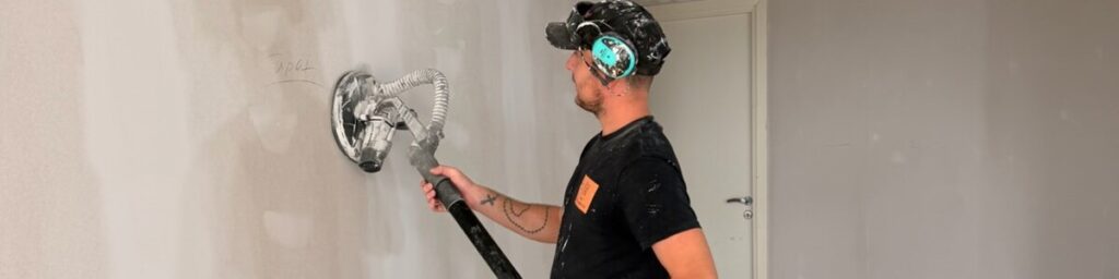 Bredspacklad vägg slipas slät inför målning, underarbete utfört av AF Byggservice i Jönköpings län