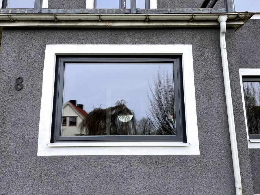 Närbild på ett nytt fönster med mörk båge monterat på en villa